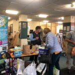 Volunteers at the library behind a table, accepting "hard to recycle" waste next to Sustainable Newport Banner
